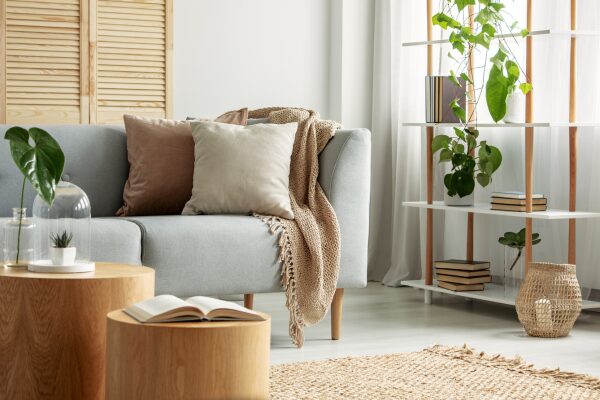 Sala compacta decorada com sofá cinza, prateleira vertical com plantas e móveis de madeira clara